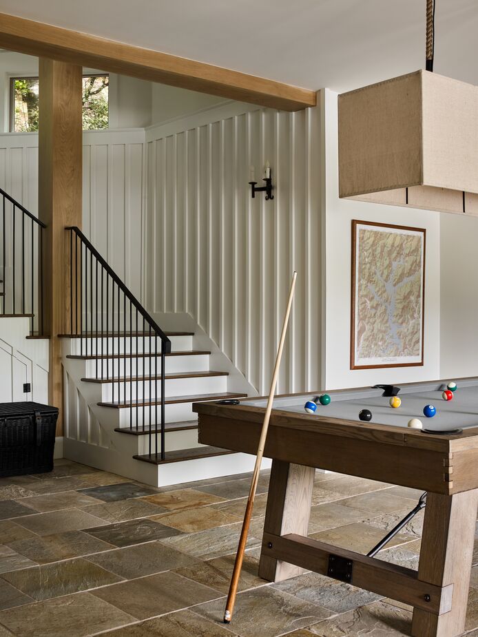 The clean lines of the pool table and the light fixture give the room a contemporary vibe that plays off the rustic materials.
